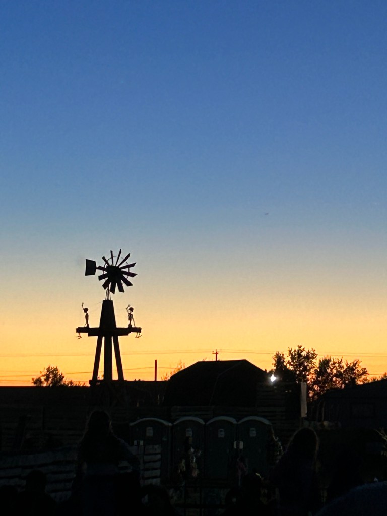 Windmill and Halloween decorations silhouetted against the sunset at Black Island Farms