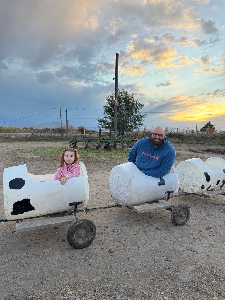 A child and adult riding the cow barrel train at Black Island Farms