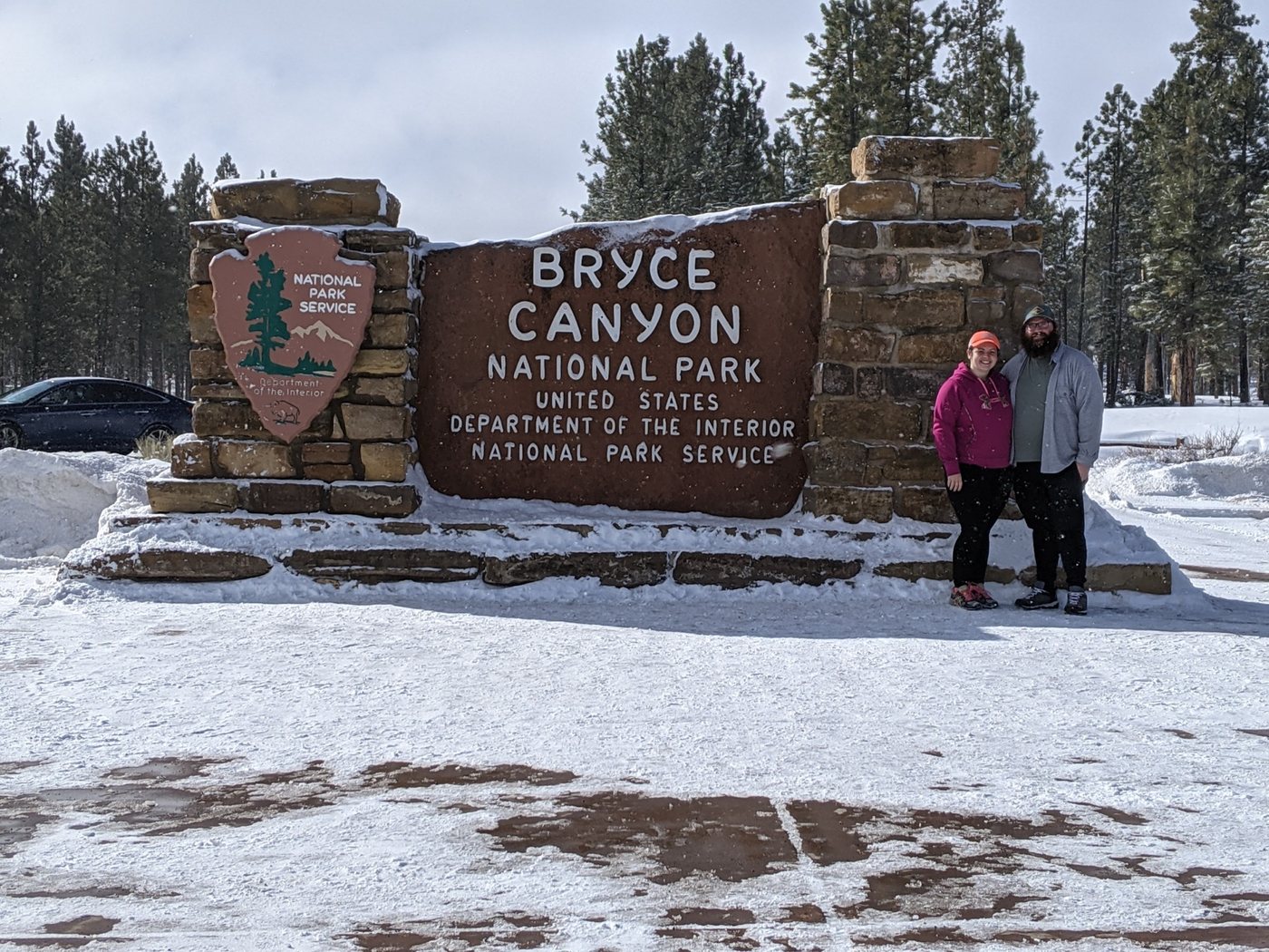 Family standing beside the Bryce Canyon National Park entrance sign in winter