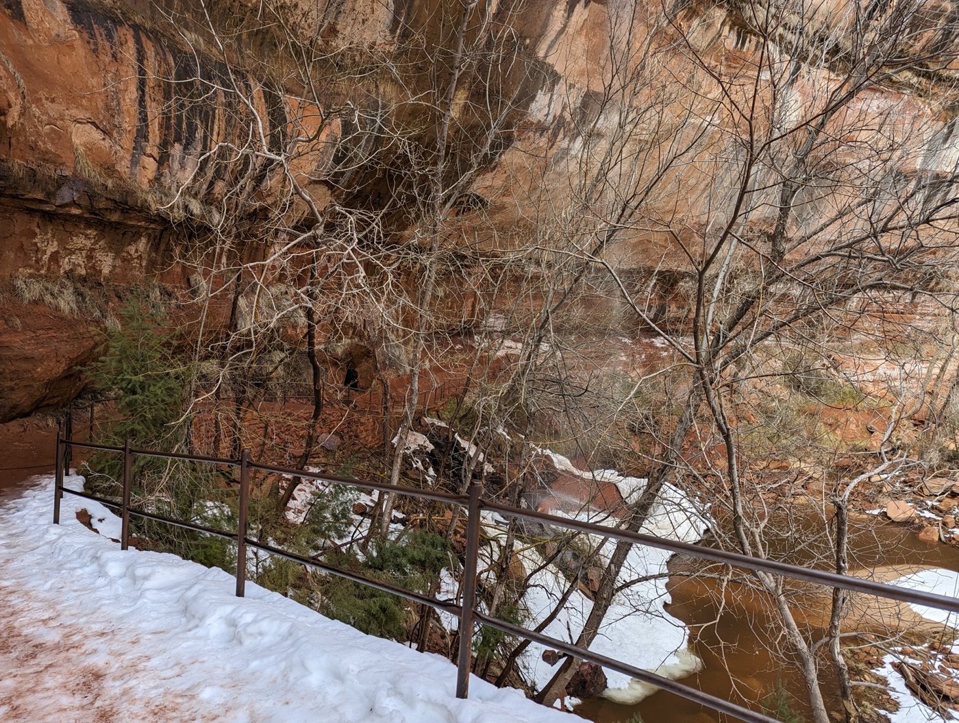 Snowy trail railing above a creek in Zion Canyon
