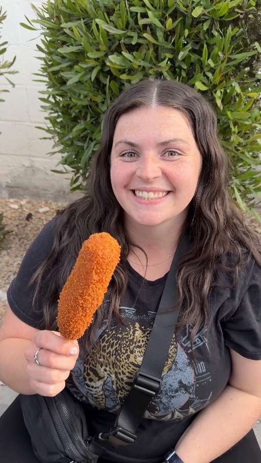Smiling while holding a Korean corn dog outside Cruncheese in Las Vegas