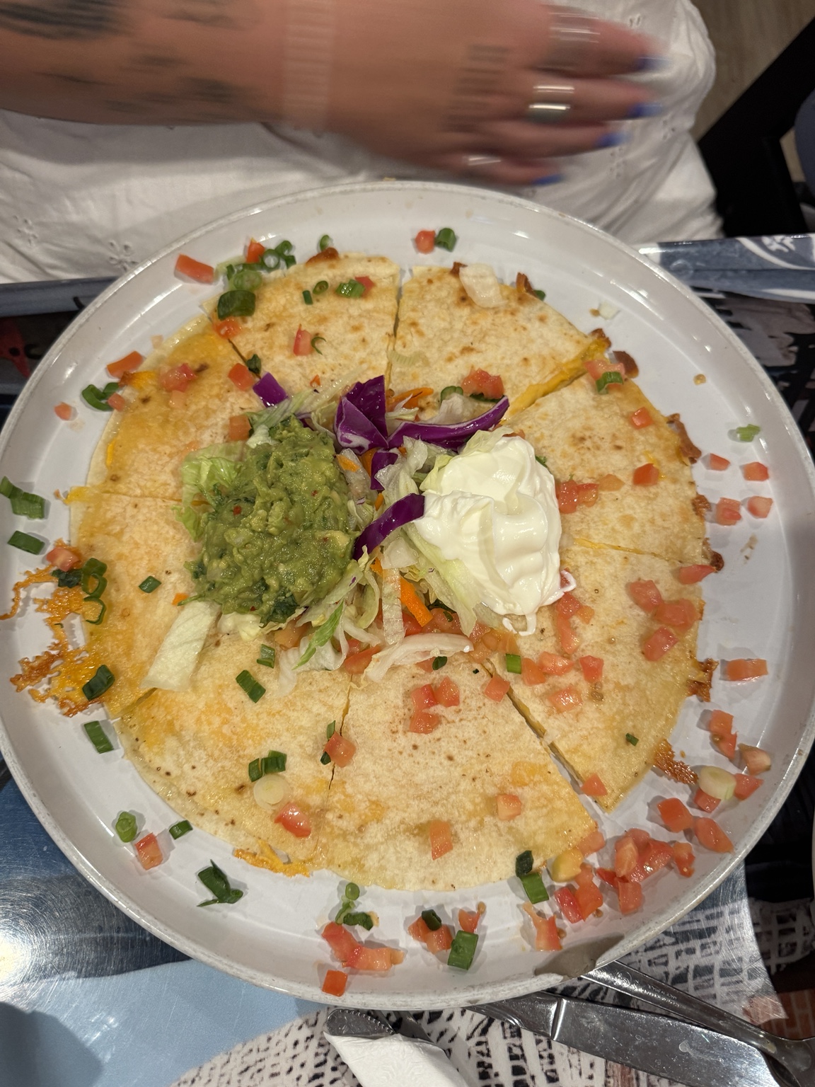 Cheesy quesadilla topped with guacamole, sour cream, and fresh vegetables